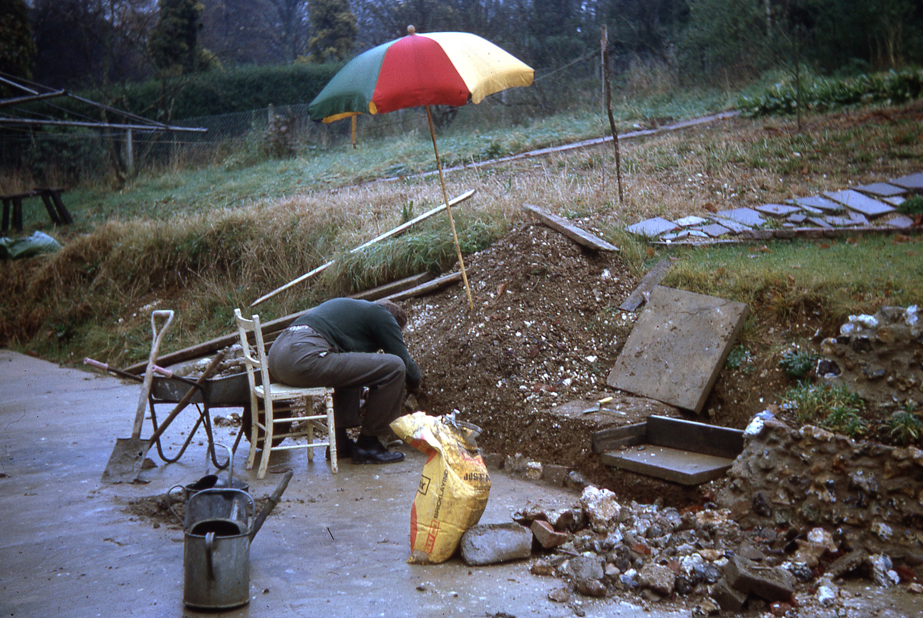 Roy building back garden retaining wall in the rain, April 1967